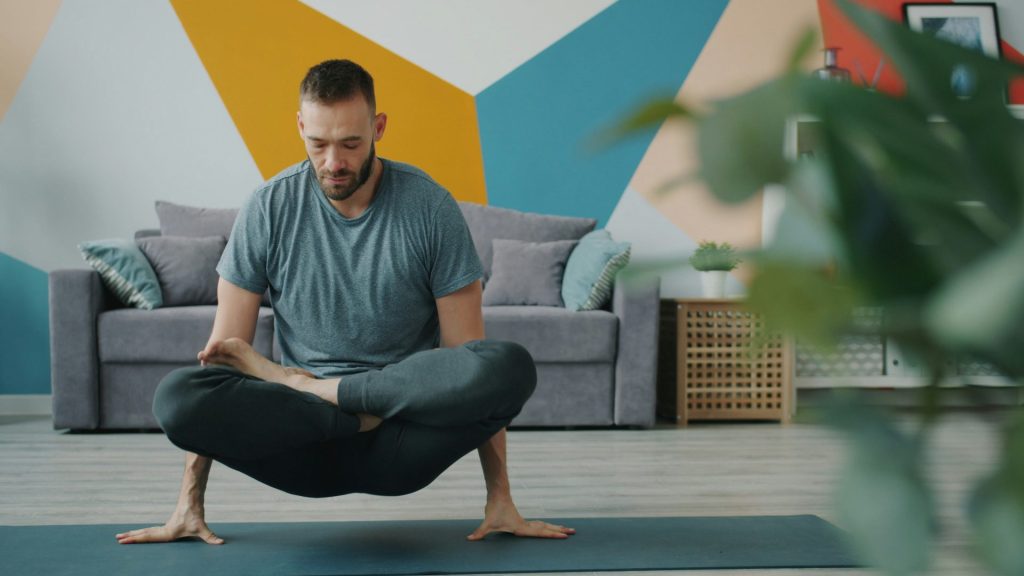 Ein Mann praktiziert Yoga auf einer Matte in einem Innenraum.